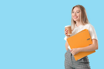 Pretty young woman with folder and cup of coffee on blue background