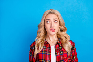 Photo of nervous blond hairdo young lady bite lip look up wear red shirt isolated on blue color background