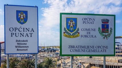 Punat/Croatia-04302018: Two signs welcoming you to enter the territory of Punat. Both of them present the emblem of the city. Sign on the left welcoming the visitors in many languages.