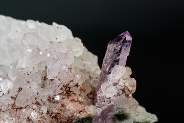 macro mineral amethyst stone in rock on a black background