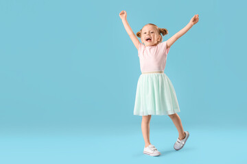 Fototapeta na wymiar Cute little girl in skirt dancing on blue background