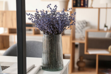 Vase with beautiful lavender flowers on table in room