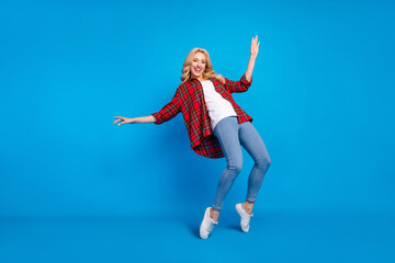 Fototapeta na wymiar Photo of funky charming young woman dressed checkered shirt dancing smiling isolated blue color background