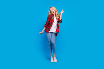 Photo of charming funky young woman dressed checkered shirt dancing smiling isolated blue color background