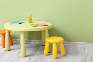 Table with chairs and stationery supplies near color wall in child room