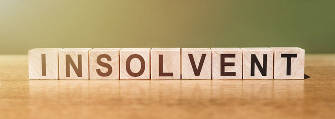 Insolvency word in wooden cubes on a green-brown background
