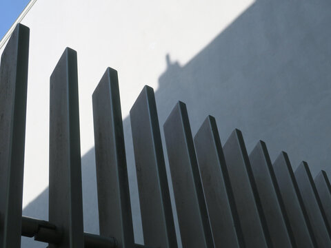 black painted metal fence in front of a white wall