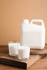 Gallon bottle and glasses of milk on wooden table