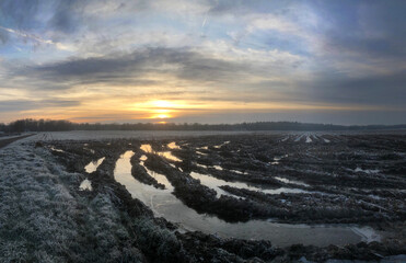 Water puddeles in muddy field. Winter at the Uffelter es Uffelte Drente Netherlands. Sunset.