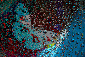 Transparent drops of water are located against the multicolored background with blue silhouette of butterfly. Abstract fantasy. 3D render.