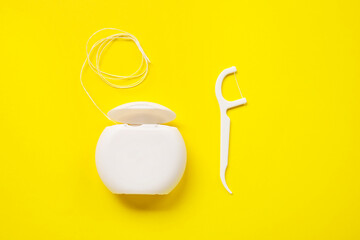 Dental floss and toothpick on yellow background
