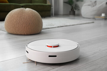 Modern robot vacuum cleaner on wooden floor in room