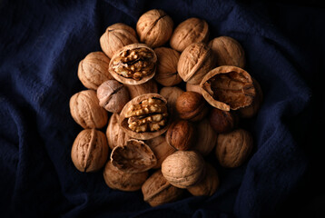 A group of walnuts on a blue old cloth by the window in a dark place (out of focus, macro)