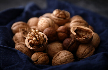 A group of walnuts on a blue old cloth by the window in a dark place (out of focus, macro)