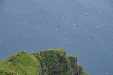 The green and blue dramatic and wild coastal landscapes in the Faroe Islands