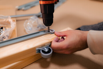 A man working on a new bed installation and using a cordless drill