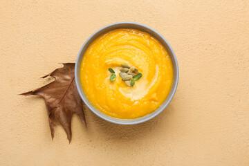 Bowl of tasty pumpkin cream soup on beige background