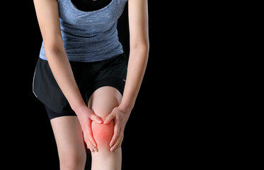 A woman in sportswear is holding a painful knee joint (marked in red)