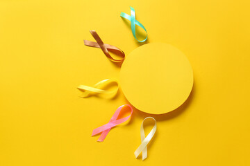 Composition with blank card and awareness ribbons on yellow background. World Cancer Day