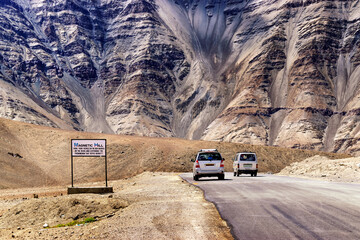 A gravity hill where slow speed cars are drawn against gravity, known as Magnetic Hill , a natural wonder at Leh, Ladakh, Jammu and Kashmir, India - Himalayan mountains in background.