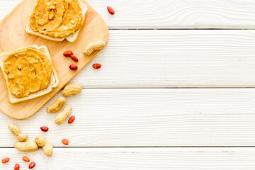 Smooth peanut butter on sandwiches with nuts. Top view