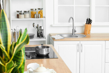 White counter with silver sink and set of knives near window in kitchen
