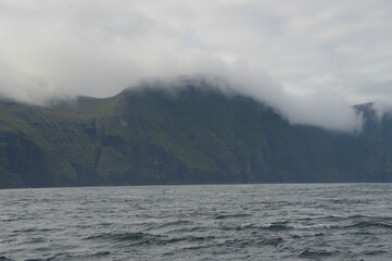 The dramatic coastline of the Faroe Islands with green mountains in the background