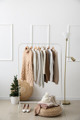 Stylish sweaters on hanger and accessories in dressing room