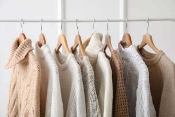 Stylish sweaters on hanger in dressing room