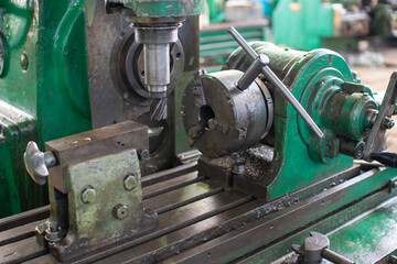 An old green milling machine with a cutter clamped in it.