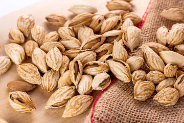 Roasted brown almond nuts in cracked shell on light table background ready to eat.