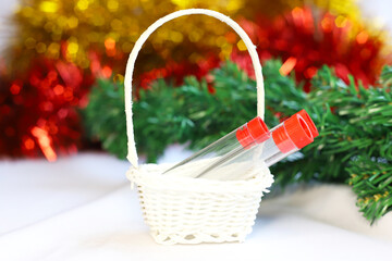 Fototapeta na wymiar Test tubes with a vaccine against the COVID-19 coronavirus lie as a gift in a basket against the background of New Year decorations. Close-up. The concept of holidays