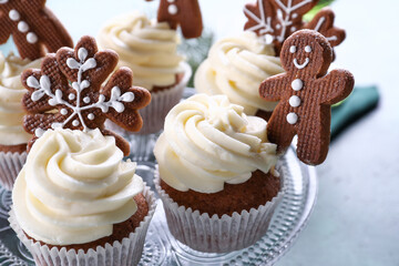 Stand of tasty Christmas cupcakes with gingerbread cookies on table, closeup