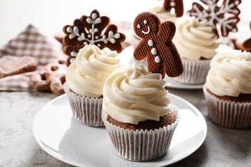 Tasty Christmas cupcakes with gingerbread cookies on light background
