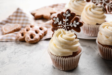 Tasty Christmas cupcakes with gingerbread cookies on light background