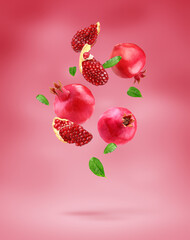 Pomegranate with slice and leafs flying on pomegranate colour background