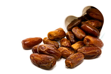Dates isolate. Dates spill out from a cup in the shape of a heart on a white background close-up. Dried fruits