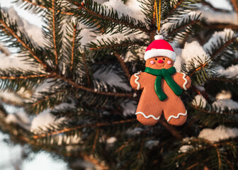 Christmas gingerbread man toy hangs on snow covered tree. Christmas holiday concept.