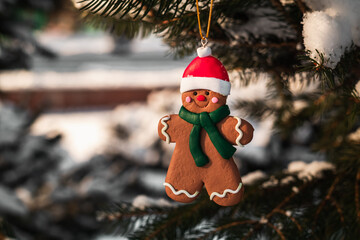Christmas gingerbread man toy close up hangs on snow covered tree. Christmas concept.