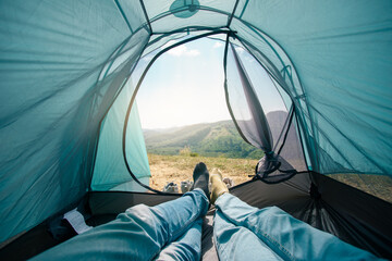 Two people lying in tent with the door tent view lookout camping on the mountain in the morning. Couple tourist camping tent on the mountain.