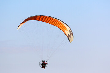 Paramotor pilot flying in a blue sky	
