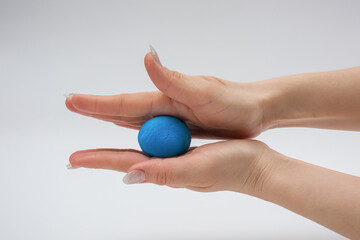 The process of modeling plasticine. A piece of blue plasticine in hand.
