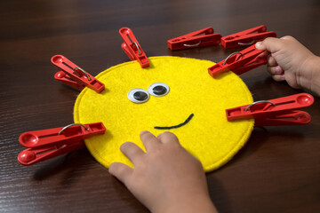 Hands of a little girl preschool age. Lesson with a colored die and clothespins. Sensory development, Fine motor skills, Montessori method, Tools, Child development concept.