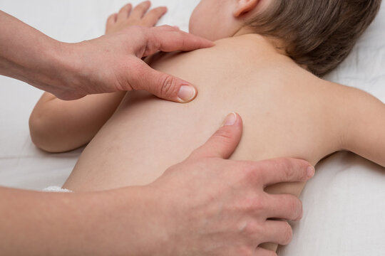 Woman hands doing a massage to white boy, close up. Kids massage. Osteopathy for the child.