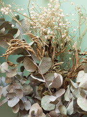Bunch of dried flowers and eucaliptus branches on green background