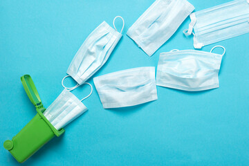 Throwing away a medical mask in a green container for recycling on a blue background. Blue face masks after use. The use of medical masks