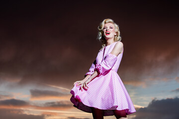 Woman in monroe dress on dramatic sky. Stylish fashion woman posing outdoor. Attractive young woman...