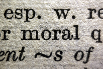 Título: Word "moral" and "violent" printed on dictionary page, macro close-up		