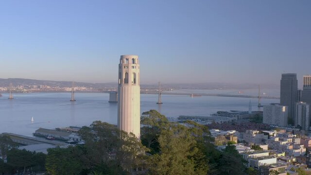 4K aerial video footage partially rotating around a tower in San Francisco, California at sunset. Golden light on tower, Bay Bridge in the background.	

