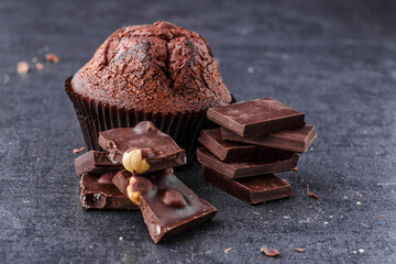 Chocolate cupcake with icing and chocolate bar in Dark lighting,Homemade delicious chocolate muffin on wooden background close-up